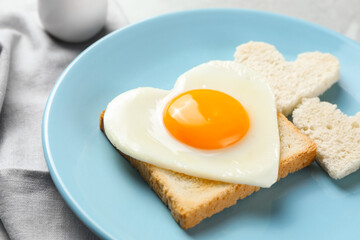 Fototapeta premium Romantic breakfast with heart shaped fried egg and toasts on table, closeup