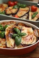 Delicious eggplant lasagna in baking dish on wooden table
