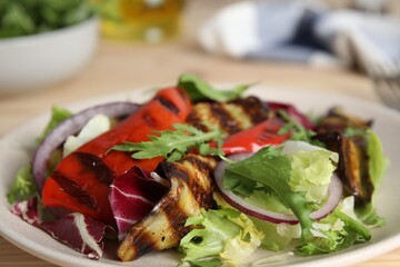 Delicious salad with roasted eggplant and arugula on plate, closeup
