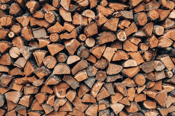 Picturesque wall of firewood logs, rustic background. Wooden pile texture. Chopped dry firewood logs stacked in a rows. Natural alternative heating source.