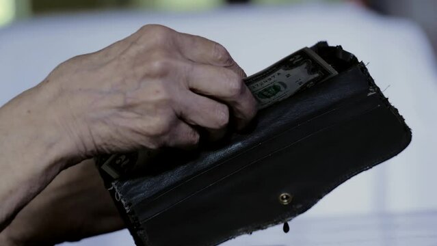An old gray wallet in the hands of a pensioner. Dollar bill. poverty