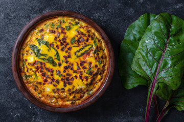 Ceramic bowl with vegetable frittata. Frittata with eggs, green beet leaves, onion, pepper, spices and cheese