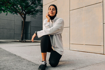 Athletic woman with a hijab looking at the camera outdoors