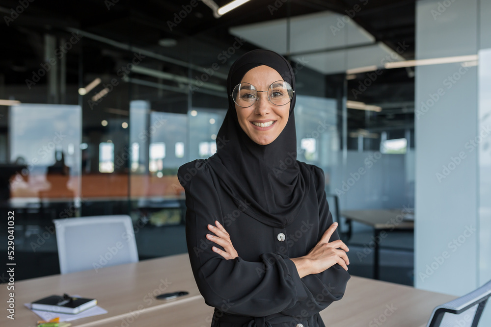 Wall mural portrait of muslim woman in hijab at work in office, business woman smiling and looking at camera wi