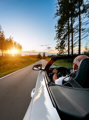 Adult man is driving with convertable car in sunny nature on a bright summer day. wide angle...