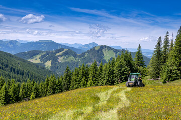 Tractor in a field in front of alpine mountain range