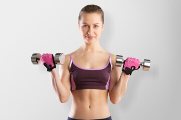 Sporty woman exercises with dumbbells. Good shape and health fitness woman weight training standing pose smile to camera.