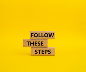 Follow these steps symbol. Wooden blocks with words Follow these steps. Beautiful yellow background. Business and Follow these steps concept. Copy space.