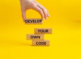 Develop your own code symbol. Concept words Develop your own code on wooden blocks. Businessman hand. Beautiful yellow background. Business and Develop your own code concept. Copy space.
