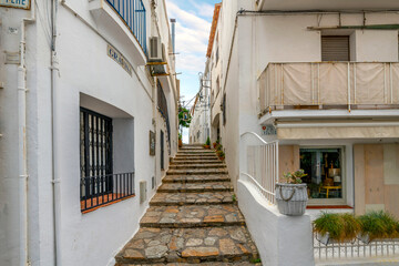 Fototapeta na wymiar A narrow hilly staircase path in the whitewashed village of Calella de Palafrugell, Spain, on the Costa Brava coast of the Mediterranean Sea.