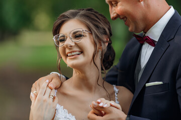 Close up laughing, romantic stylish married couple of man and woman in glasses and wedding dress...