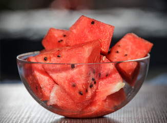 Glassware with juicy and sweet watermelon cubes on a wooden table. Slices of sweet juicy watermelon in a glass plate on a hot summer day.