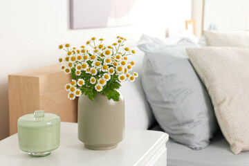 Fototapeta na wymiar Beautiful bouquet of chamomile flowers on white nightstand in bedroom, space for text. Interior element
