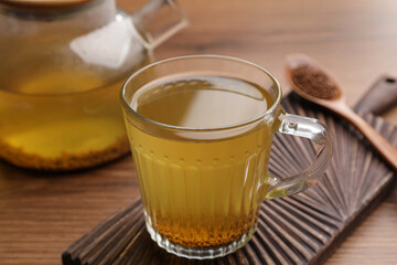 Cup of aromatic buckwheat tea and granules on wooden table