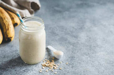 Oat milk banana protein smoothie in jar. Healthy vegan fitness or sport drink, liquid food. Copy...