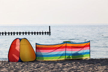 Fototapeta Parawan  słoneczny na plaży nadmorskiej w wakacje razem z parawanem na wiatr. obraz