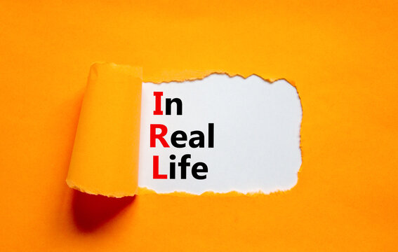 IRL in real life symbol. Concept words IRL in real life on white paper on a beautiful orange background. Business and IRL in real life concept. Copy space.