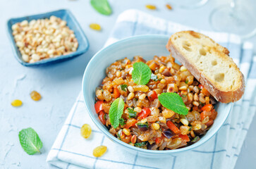 Sicilian Eggplant pine nuts Caponata in a bowl on a wood background