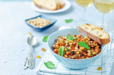 Sicilian Eggplant pine nuts Caponata in a bowl on a wood background