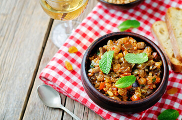 Sicilian Eggplant pine nuts Caponata in a bowl on a wood background