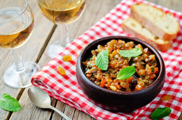 Sicilian Eggplant pine nuts Caponata in a bowl on a wood background