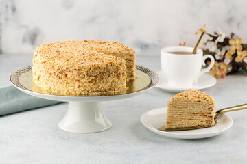 Sliced Napoleon cake on cake stand on white concrete background