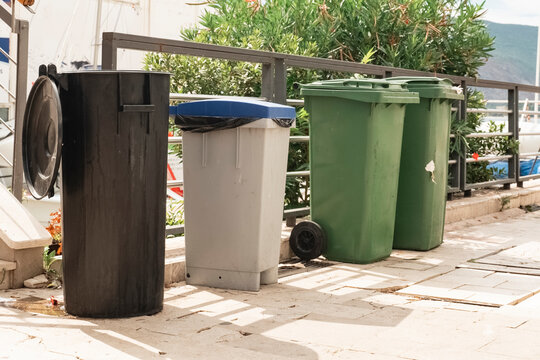 four plastic garbage cans of different colors are on the territory of the restaurant, Garbage cans on the street. Points of distribution and recycling of garbage. Environmental pollution.