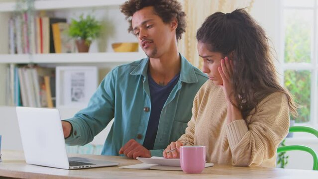 Worried couple at home in debt using laptop to check bills and home finance preparing a business plan for online store - shot in slow motion