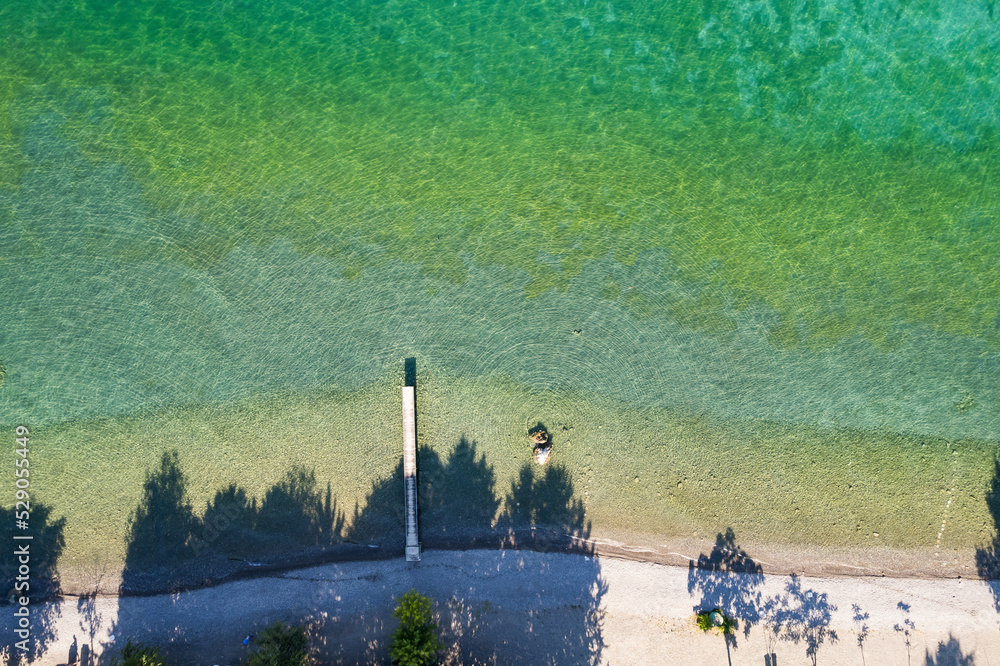 Wall mural straight view on pier of the air on the shore of ohrid lake in summer with crystal clear water of ma