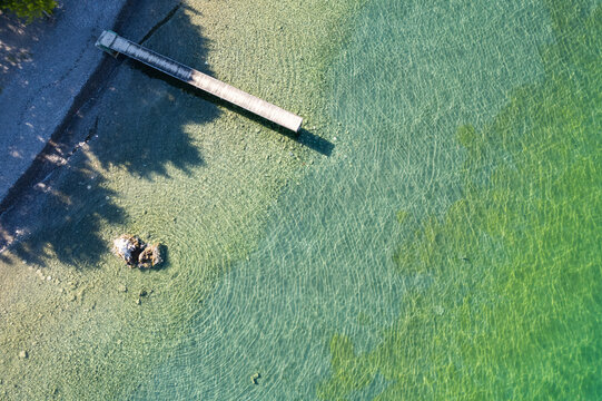 Straight view on pier of the air on the shore of Ohrid lake in Summer with crystal clear water of many colours