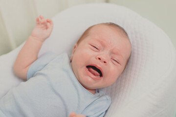 A hungry baby is crying in the crib . Baby crying. Children 's emotions . Pain during teething. A hungry child. Children's colic in the stomach.