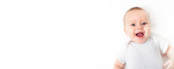 The baby lies on a white background and smiles at the camera . Advertising of children's goods. A...
