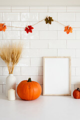 Thanksgiving frame mockup with pumpkins, vase of wheat, garland of leaves on tile wall background.