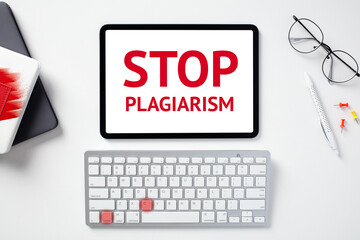 Stop plagiarism concept. Office desk table with keyboard, paper notebooks, glasses, tablet with...