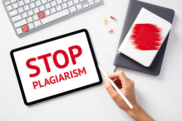 Stop plagiarism concept. Office desk table with keyboard, paper notebooks, tablet. Message STOP...