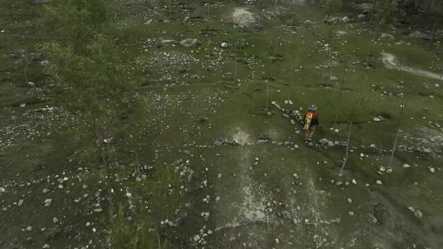 Drone flights in top of the back of  a person walking in a green area in the mountains, filmed close to Khalpu in Pakistan