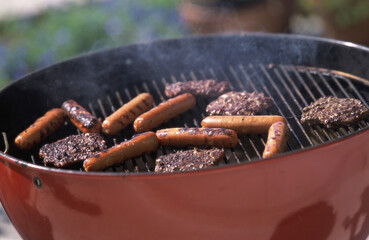 Close-up of hamburgers and hot dogs cooking on a barbecue grill