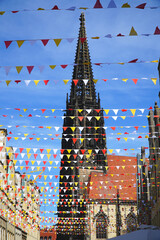 Tower of St. Lambert Church (Lamberti Church) in Münster behind colorful pennant strings above the street. City of Münster, North Rhine Westphalia, Germany. - obrazy, fototapety, plakaty
