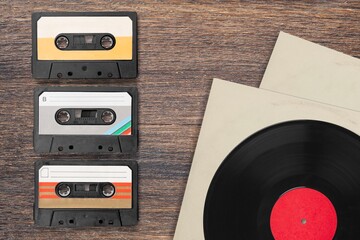 Vinyl records, cassette tapes and cassette recorder on table. Retro music style. 80s music party....