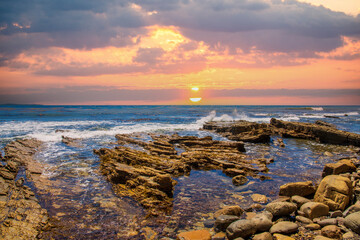 a gorgeous summer landscape at the beach with blue ocean water and sharp rocks long the shore with...