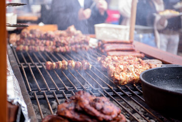 Cooking meat dishes in a summer restaurant on the street. Assorted delicious grilled meat with vegetables over charcoal barbecue.