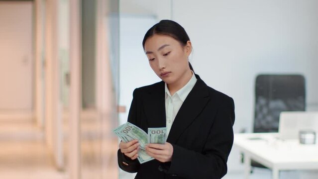Professional asian woman bookkeeper counting money at office, checking and authenticating them, empty space