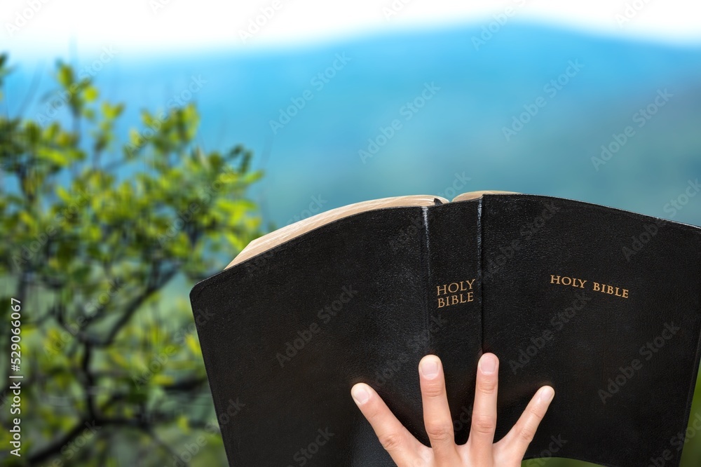 Wall mural christian holds bible in hands. concept for faith, spirituality and religion. peace, hope.