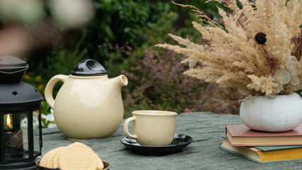 Keep warm, autumn tea party. Mug and teapot on table outdoors.