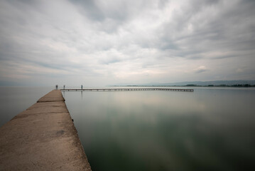 Person at pier, iznik lake and pier on shore with a person and clouds boats and silhouettes