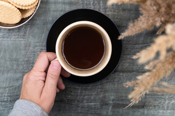 Hand holds mug of black coffee, drinking outdoors. Keep warm. Autumn mood.