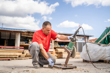 Man use grinder to cut iron armature at warehouse
