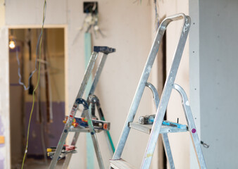Photo of stepladders with tools in empty room. Reconditioning work in living accommodation..