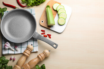 Empty frying pan, fresh vegetables and basil on wooden table, flat lay. Space for text