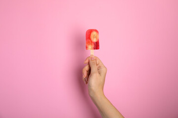 Woman holding berry popsicle on pink background, closeup